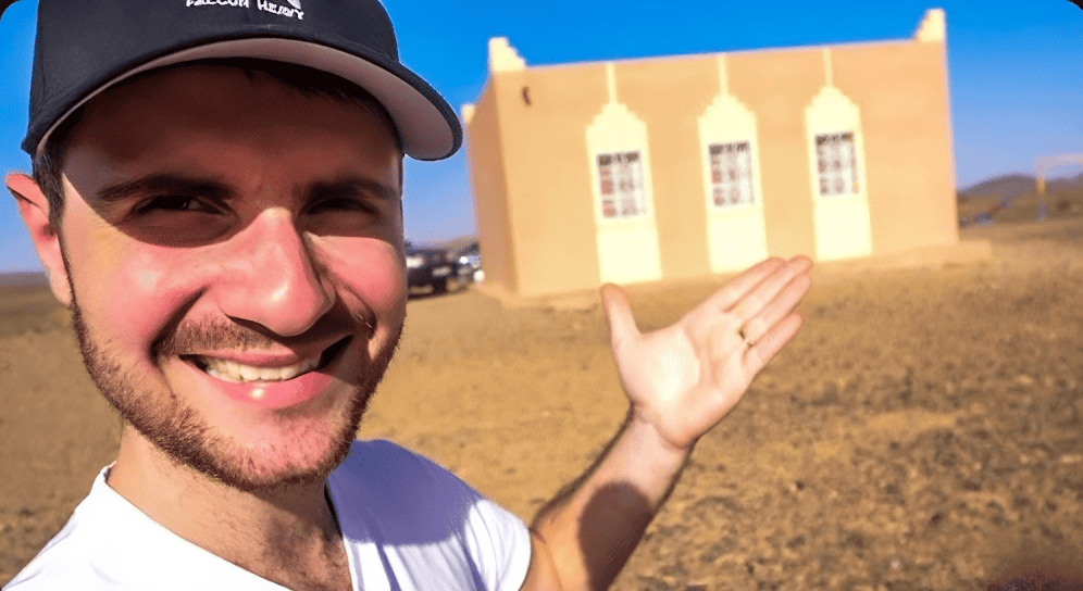 Photo d'Amixem, devant un bâtiment construit grâce à l'association dont il est le parrain et par l'argent que lui et un autre Youtubeur ont donné